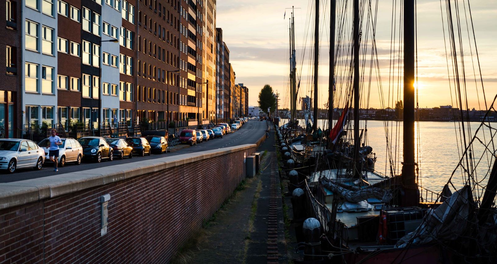 afbeelding van een ondergaande zon aan de kade met boten op Java-eiland Amsterdam.