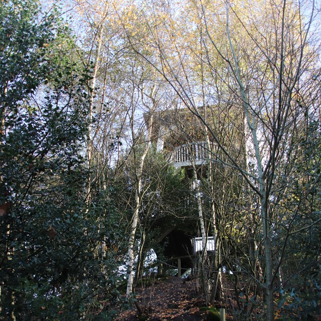 afbeelding van een uitkijktoren, verscholen tussen de bomen.