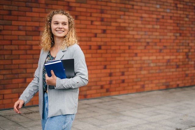 foto van een vrouw die met werkspullen in haar hand wandelt.