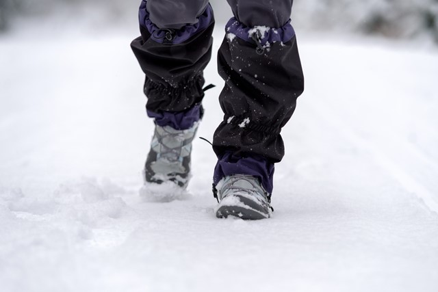 afbeelding van de voeten van iemand die door de sneeuw loopt.