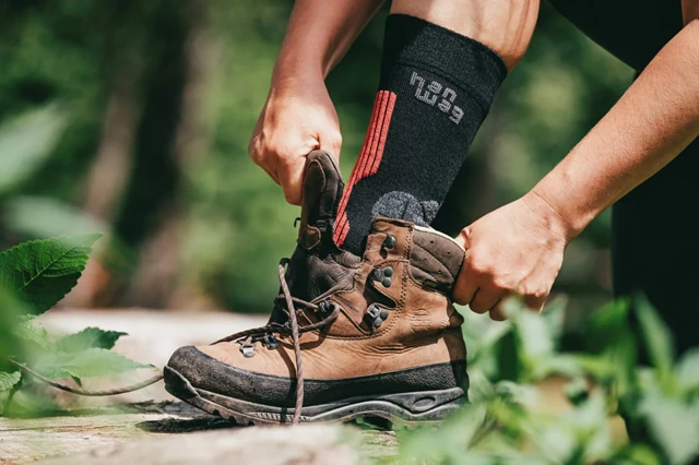 afbeelding van iemand die zijn schoen aantrekt met wandelsokken aan.
