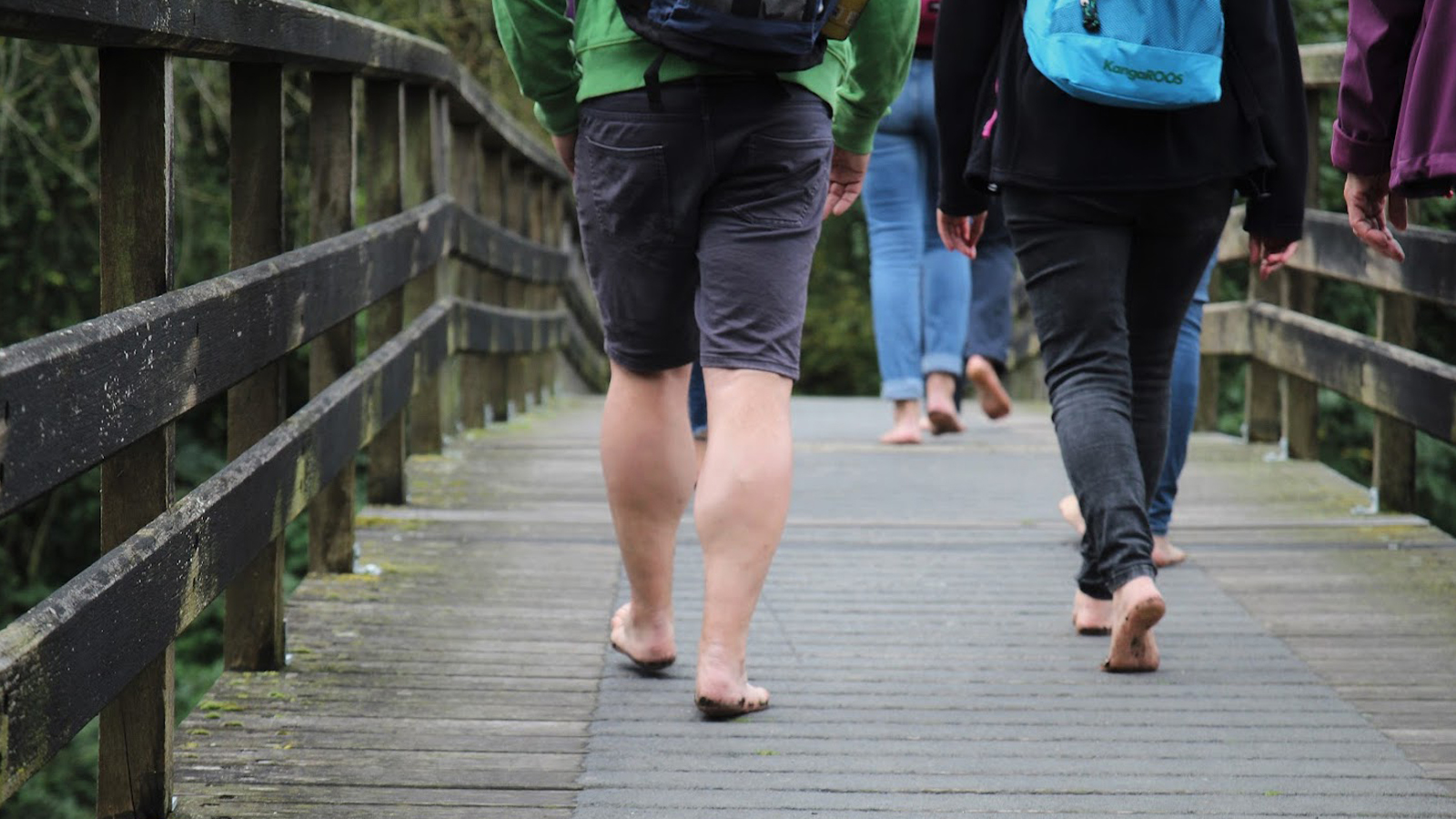Mensen wandelen met blote voeten over een bruggetje