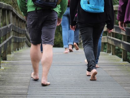Mensen wandelen met blote voeten over een bruggetje