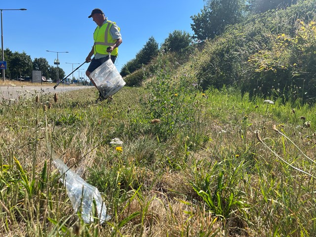 afbeelding van de Zwerfinator in actie, plandelend in het gras.