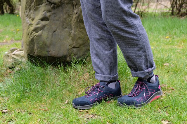 wandelschoenen in het gras naast een grote kei.