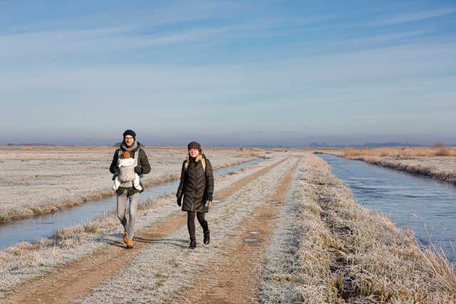 Duo met baby wandelend tussen twee sloten in winterse omstandigheden