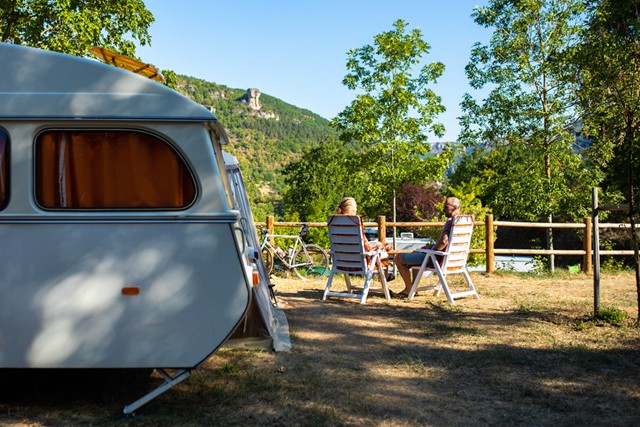 afbeelding van een stel bij hun caravan in de zon.