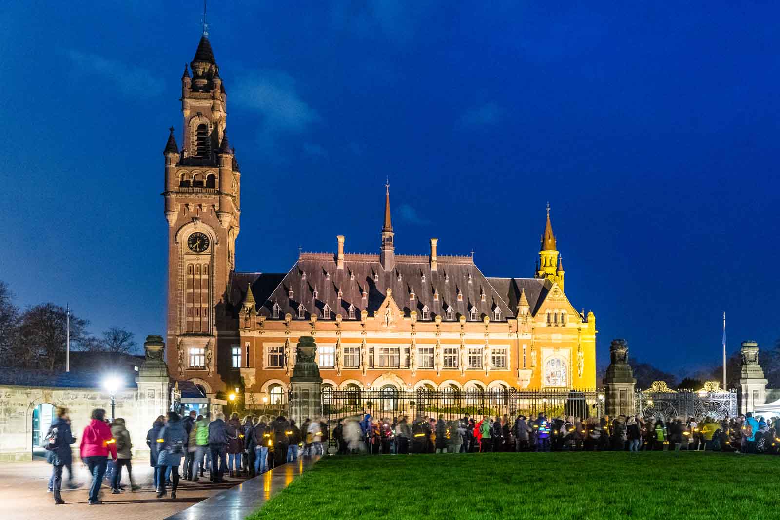 afbeelding van een groep wandelaars langs een Haagse highlight, verlicht in de avond.