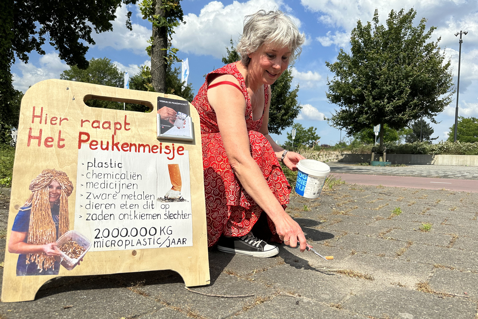 Het Peukenmeisje raapt sigarettenpeuken van de straat