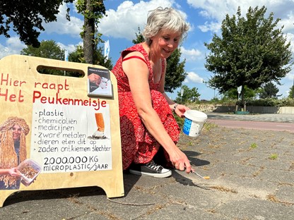 Het Peukenmeisje raapt sigarettenpeuken van de straat