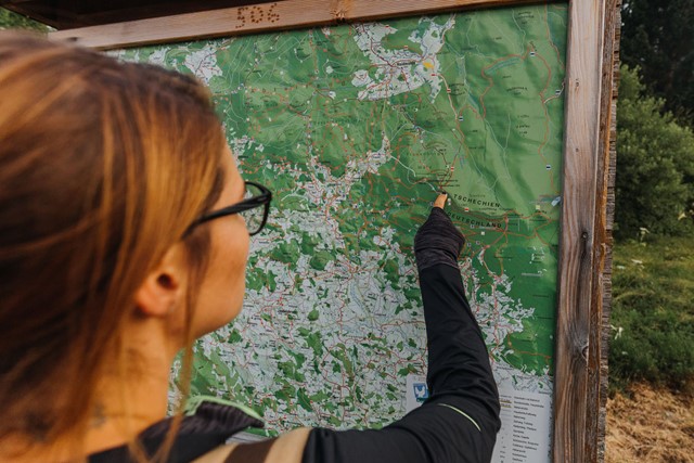 afbeelding van een wandelaar die met haar vinger wijst op de Tsjechische routekaart.