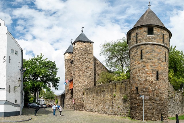 Zicht op de historische Helpoort in Maastricht met wandelaars op de weg voor de poort