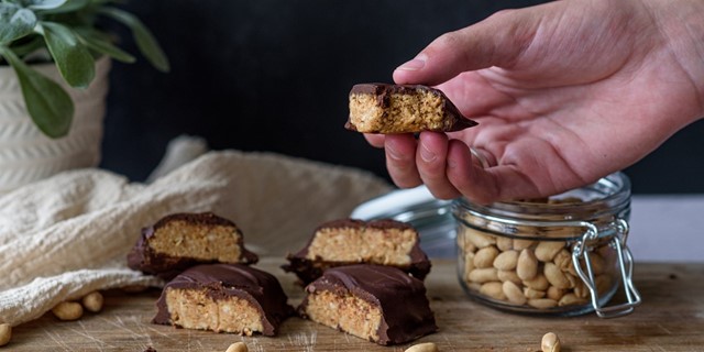 Hand pakt zelfgemaakte snack (snickers)