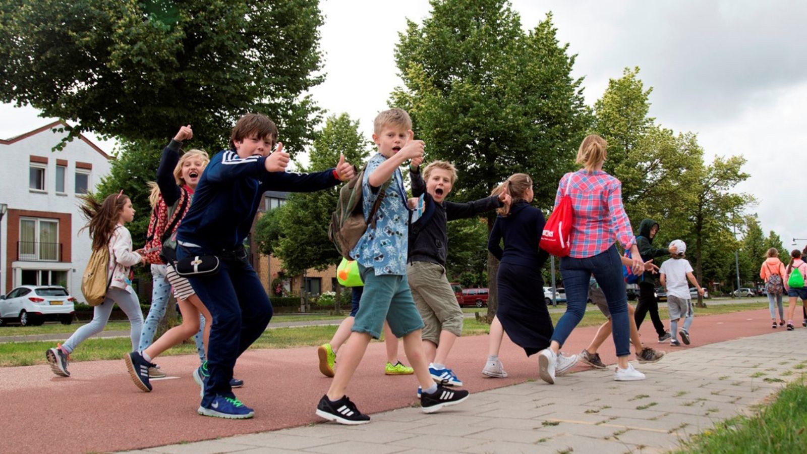Avond4daagse: een wandelfeestje voor iedereen; Vrolijke kinderen wandelen en steken duim op
