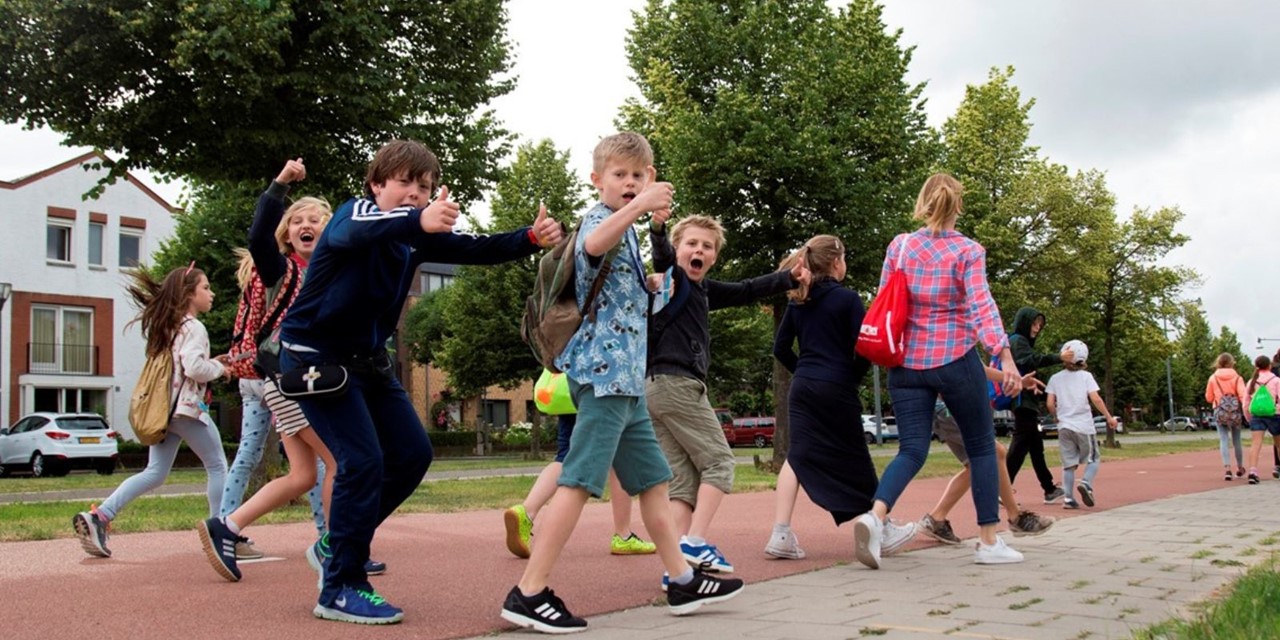 Avond4daagse: een wandelfeestje voor iedereen; Vrolijke kinderen wandelen en steken duim op