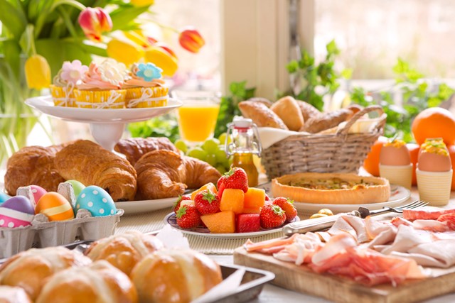 afbeelding van een tafel vol lekkers, zoals broodjes en fruit en eieren.