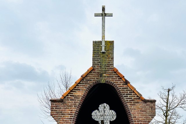 de top van een kapelletje met een kruis.
