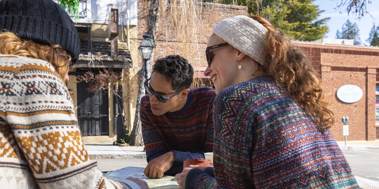 Drie wandelaars die de weg zoeken met een kaart.