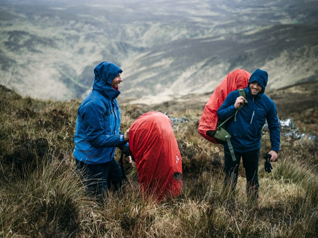 Twee mannen tijdens een bergtocht met regenjassen en grote tassen