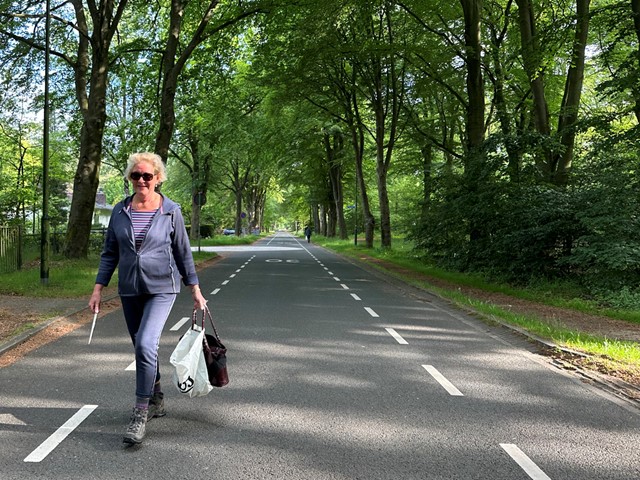 vrouw loopt op de weg met afvalgrijper en vuilniszak om te plandelen.