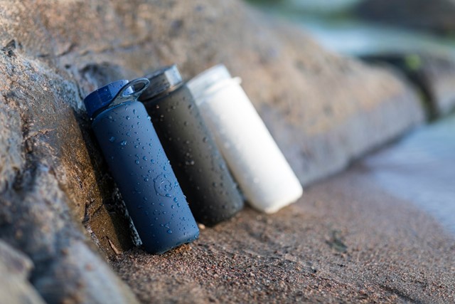 Waterflessen op een rots bij water tijdens een hike