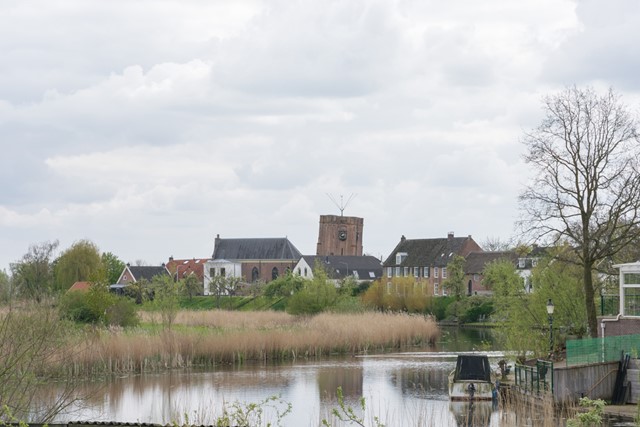 rivier met daarachter huizen en een scheve toren in Acquoy.