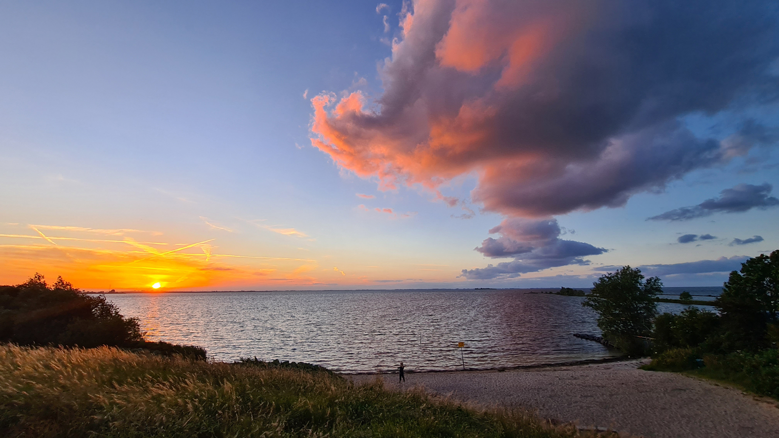 afbeelding van een zonsondergang aan het water, met felle kleuren