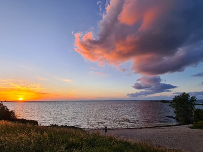 afbeelding van een zonsondergang aan het water, met felle kleuren