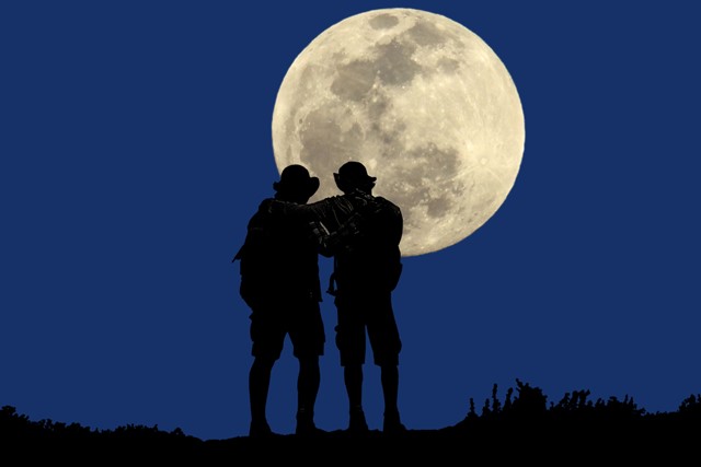 afbeelding van 2 wandelaars in het donker bij volle maan.