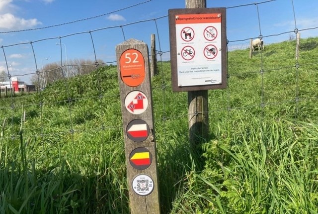Wandelknooppuntpaaltje met routecijfers langs een wandelroute