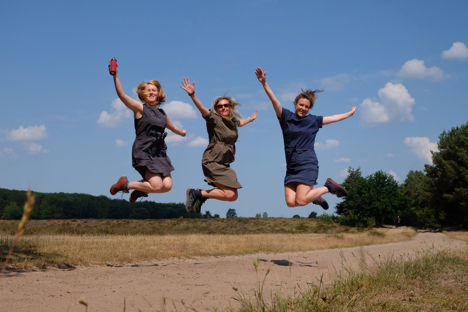drie vrouwen springen in de lucht in hun wandeljurkjes.