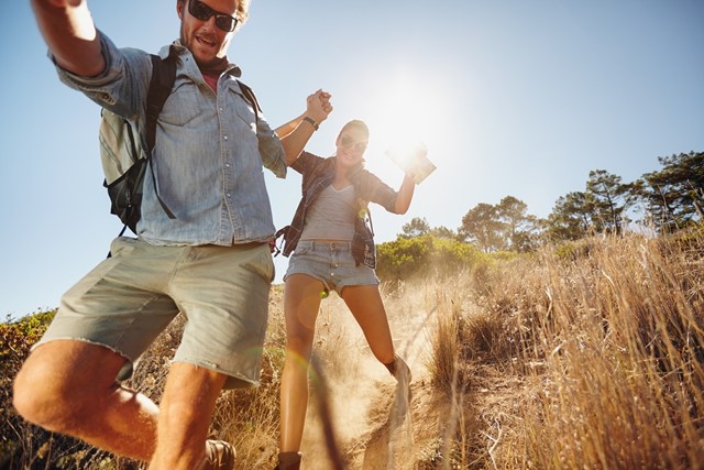 Man en vrouw rennen bij zonnige wandeling van een zandberg af