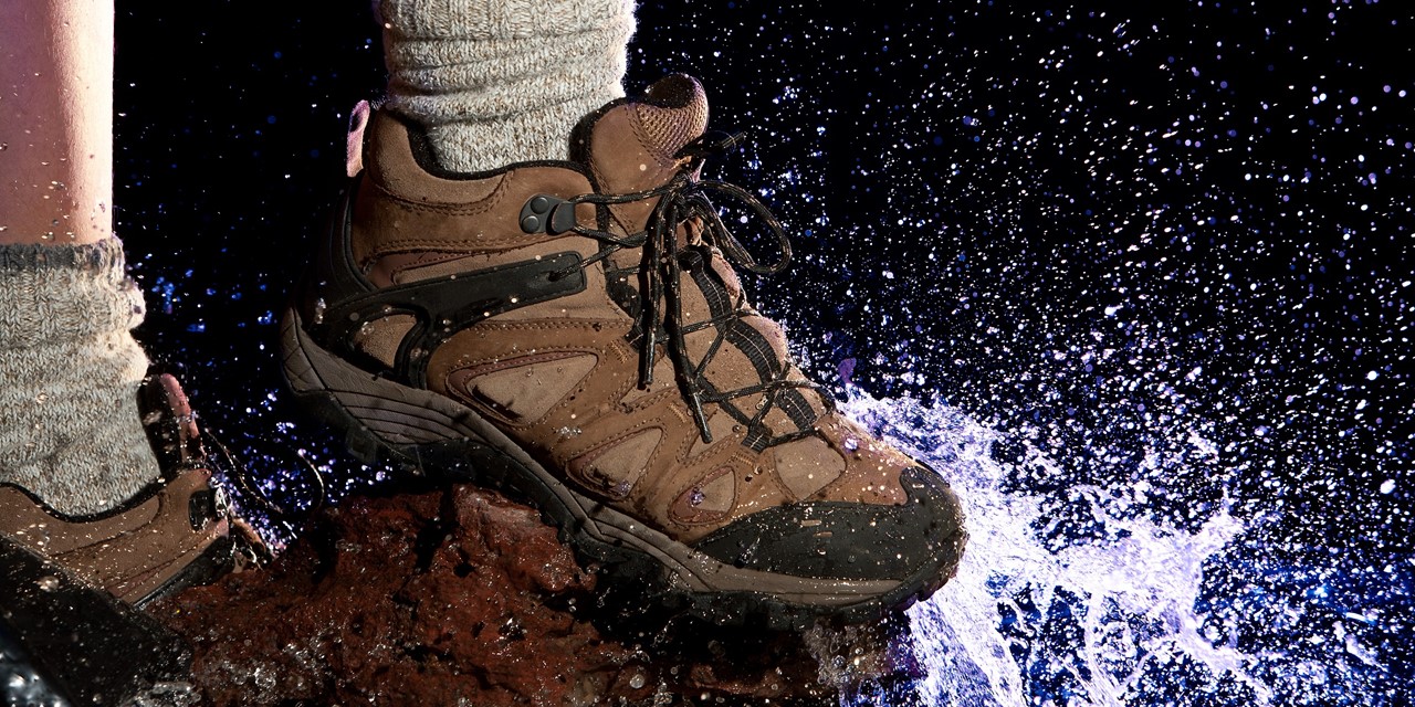 Waterdichte wandelschoenen op een rots bij een plas water
