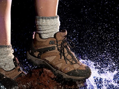 Waterdichte wandelschoenen op een rots bij een plas water