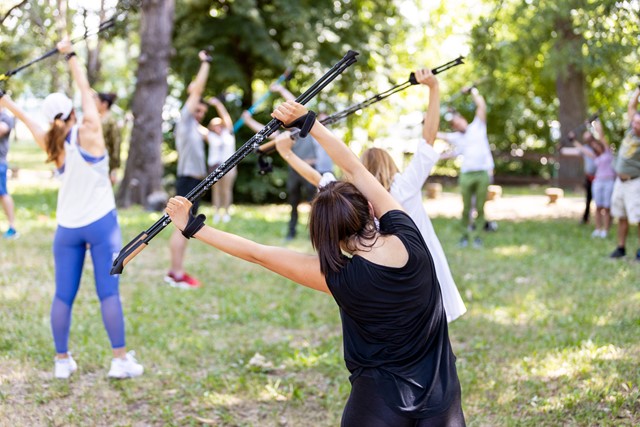 groep mensen doet rekoefeningen met stokken in een park