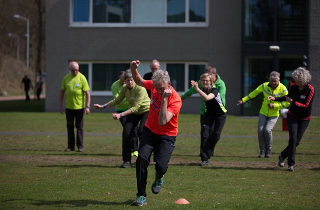 Mannen en vrouwen in sportkleding op een veld die een oefening doen