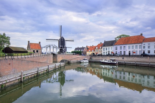 afbeelding van een gracht in Heusden met een molen.