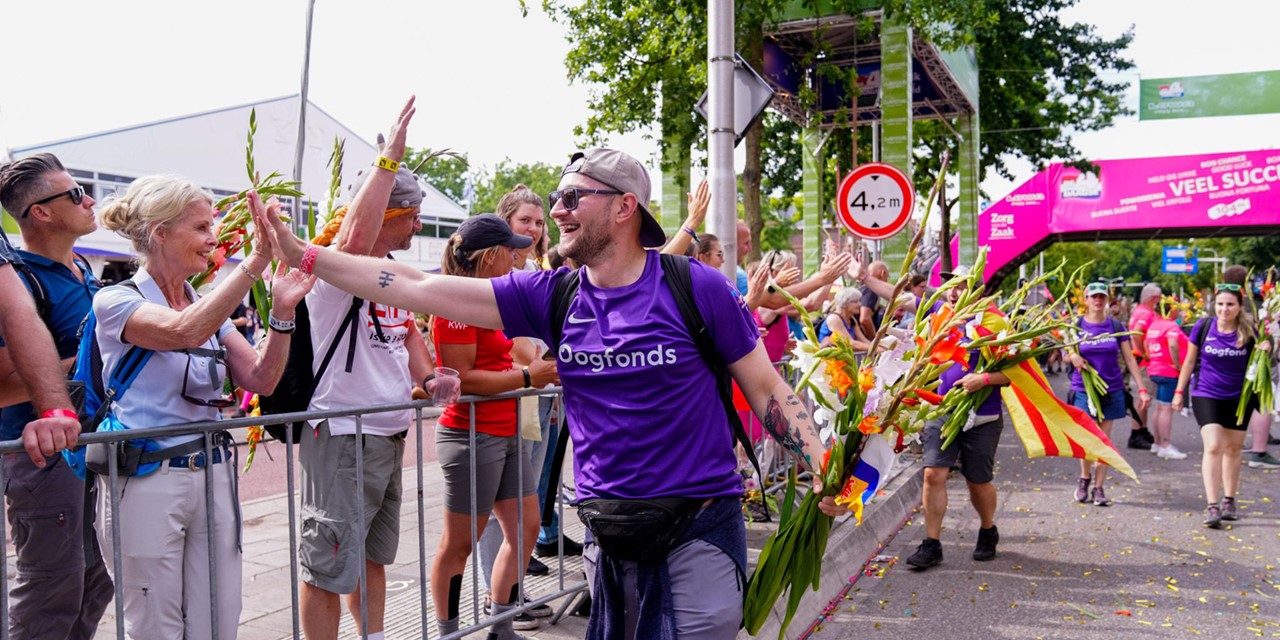 man geeft highfive tijdens de 4Daagse Nijmegen in Oogfonds-shirt.