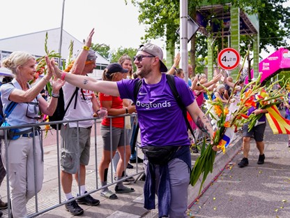 man geeft highfive tijdens de 4Daagse Nijmegen in Oogfonds-shirt.