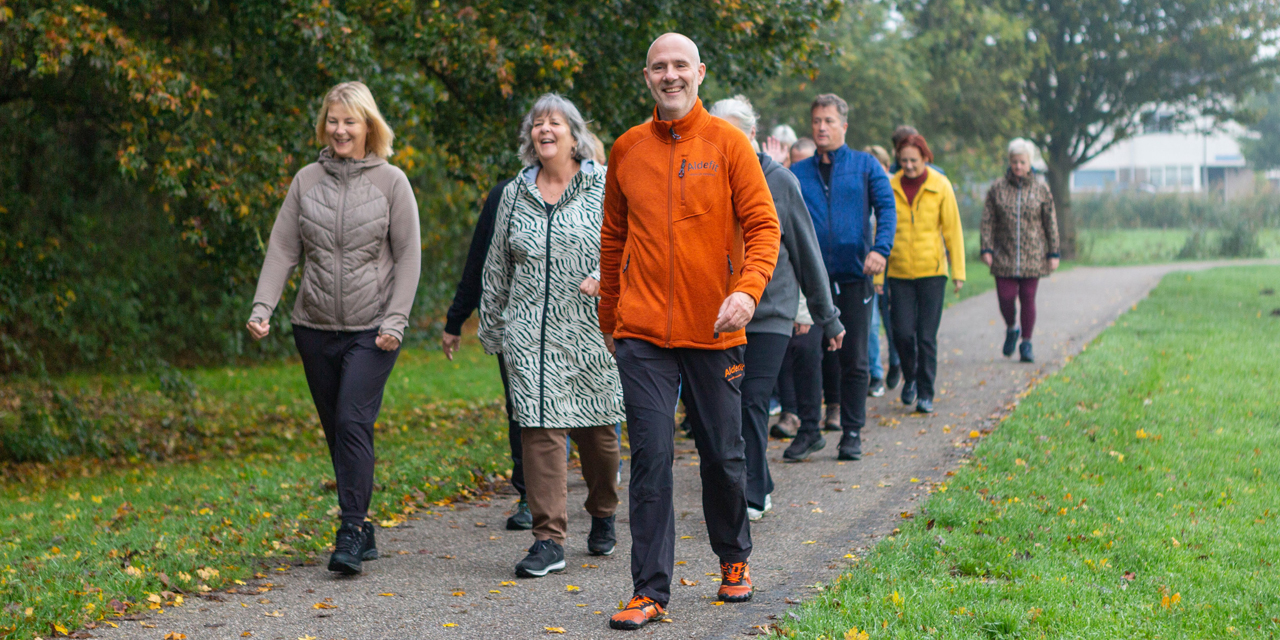 Groep wandelaars op een pad met een wandeltrainer voorop