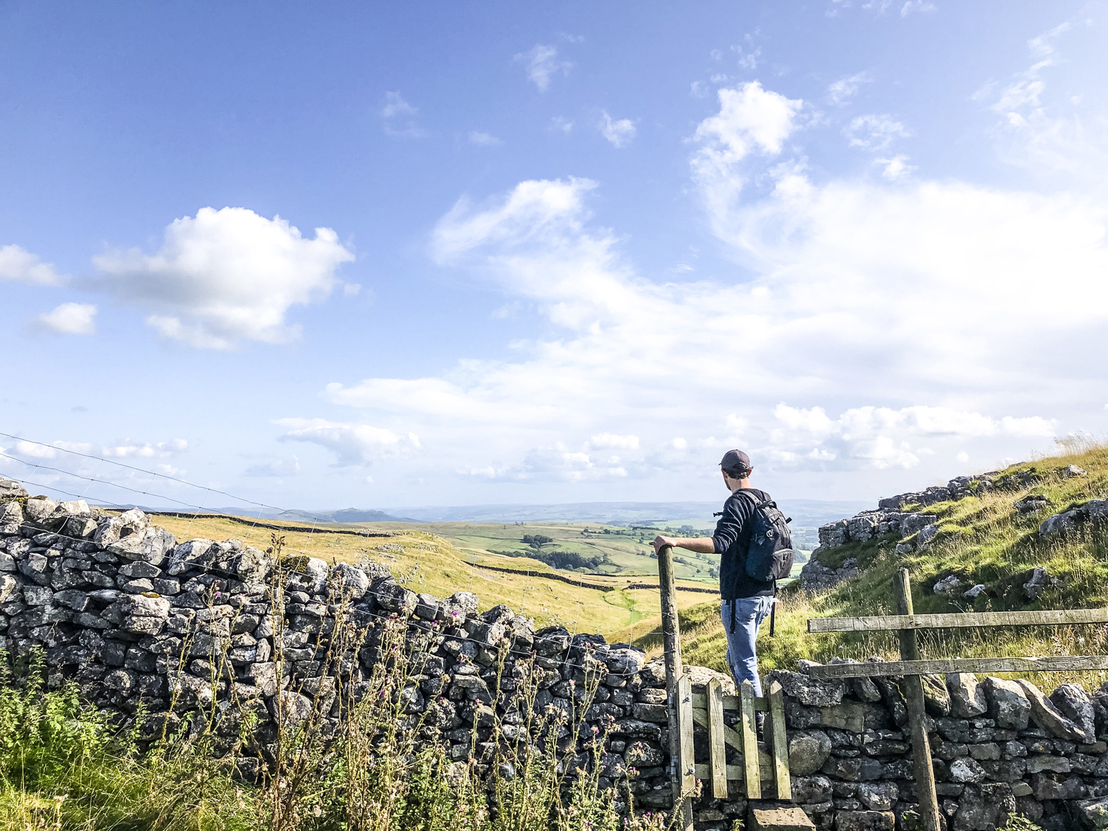 een wandelaar kijkt uit over het weidse landschap in Malham North Yorkshire.