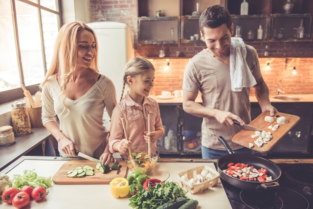 afbeelding van een gezin dat een gezonde maaltijd kookt.
