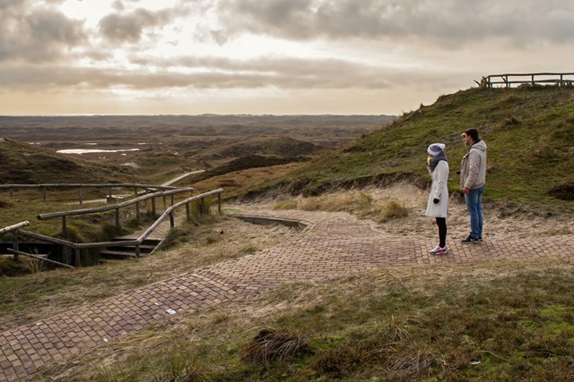 afbeelding van twee wandelaars die uitkijken of het landschap bij een bunker in Den Hoorn.