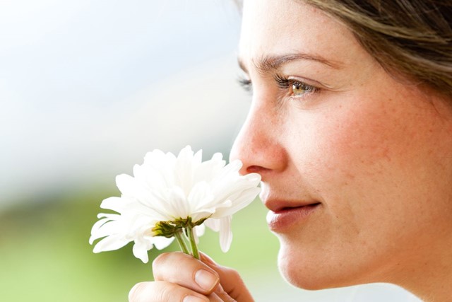 afbeelding van een vrouw die aan een bloem ruikt.