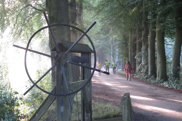 afbeelding van wandelaars en op de voorgrond een rad.