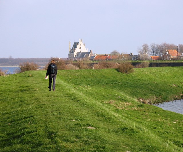 Persoon wandelend over een dijk van gras