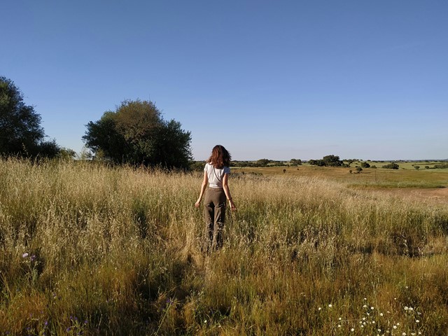Foto van een vrouw in een veld met volop ruimte om zich heen om frisse ideeen op te doen 