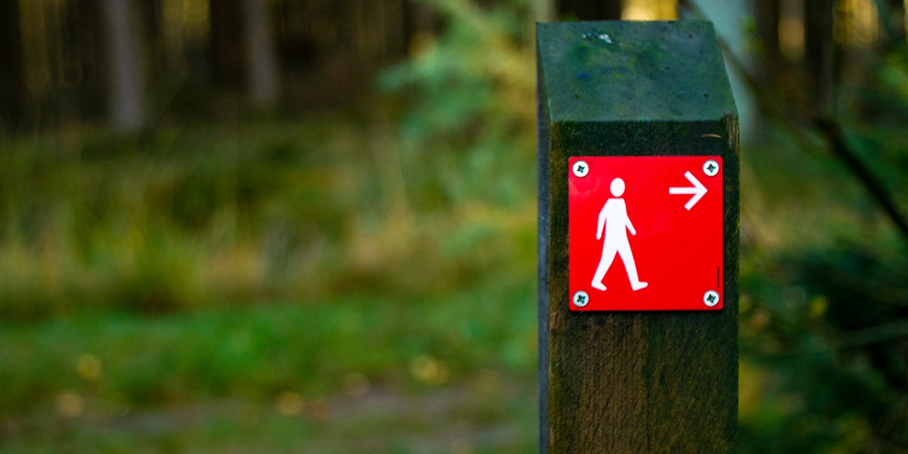 afbeelding van een rood bordje met een pijl voor wandelaars.
