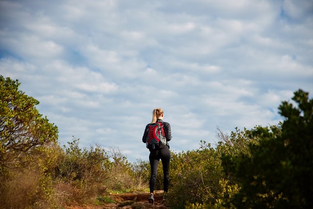 Vrouw met rode rugzak tijdens wandeling in natuur
