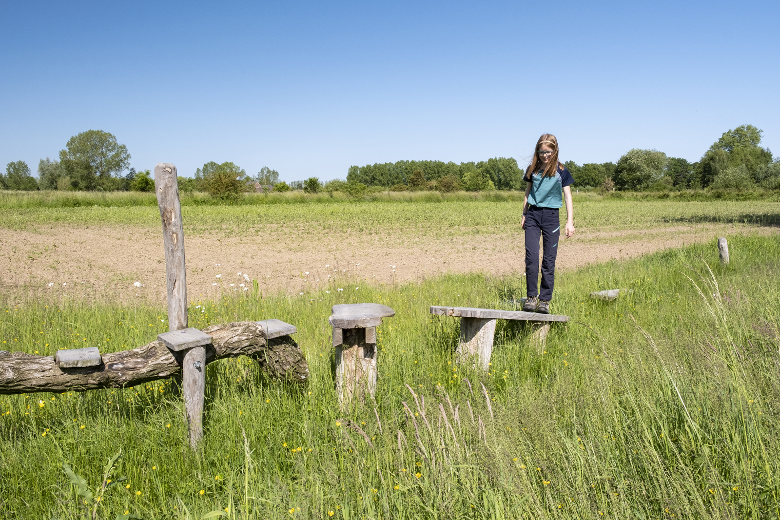 Agnes loopt over een avontuurlijk bruggetje over het grasland.
